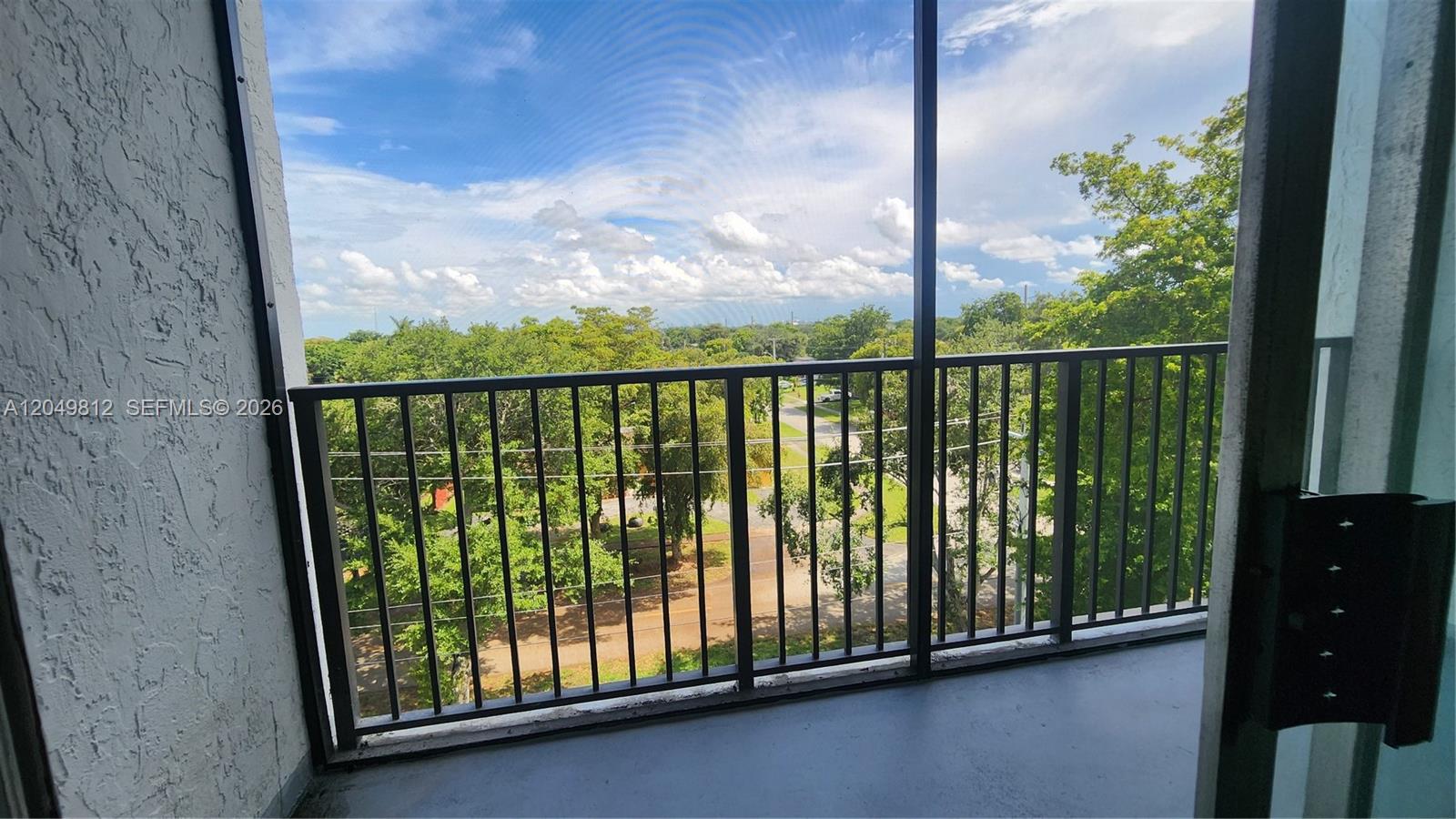A balcony with a metal railing and screen enclosure overlooks a road and trees — 7541 NW 16th St # 1507, Plantation FL 33313, PLANTATION, FL