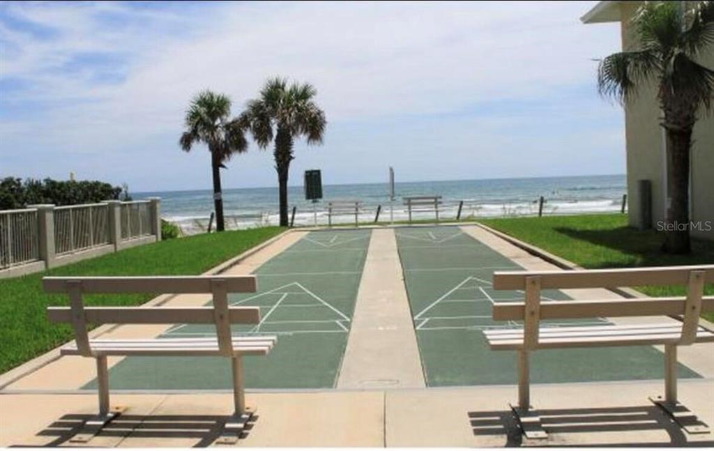 A shuffleboard court sits on a grassy lawn overlooking the ocean with two benches — 4225 S ATLANTIC AVENUE UNIT 236, NEW SMYRNA BEACH, FL