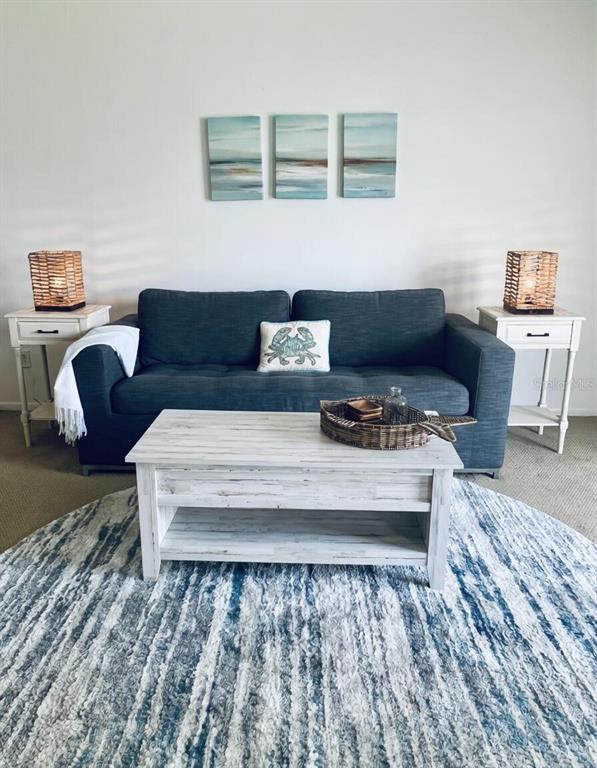 A living room features a dark blue sofa, white coffee table, and coastal-themed wall art — 4225 S ATLANTIC AVENUE UNIT 236, NEW SMYRNA BEACH, FL