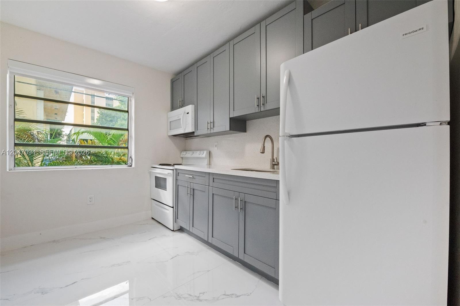 A kitchen features gray cabinets, white appliances, white countertops, and white marble-look tile flooring — MIAMI, FL