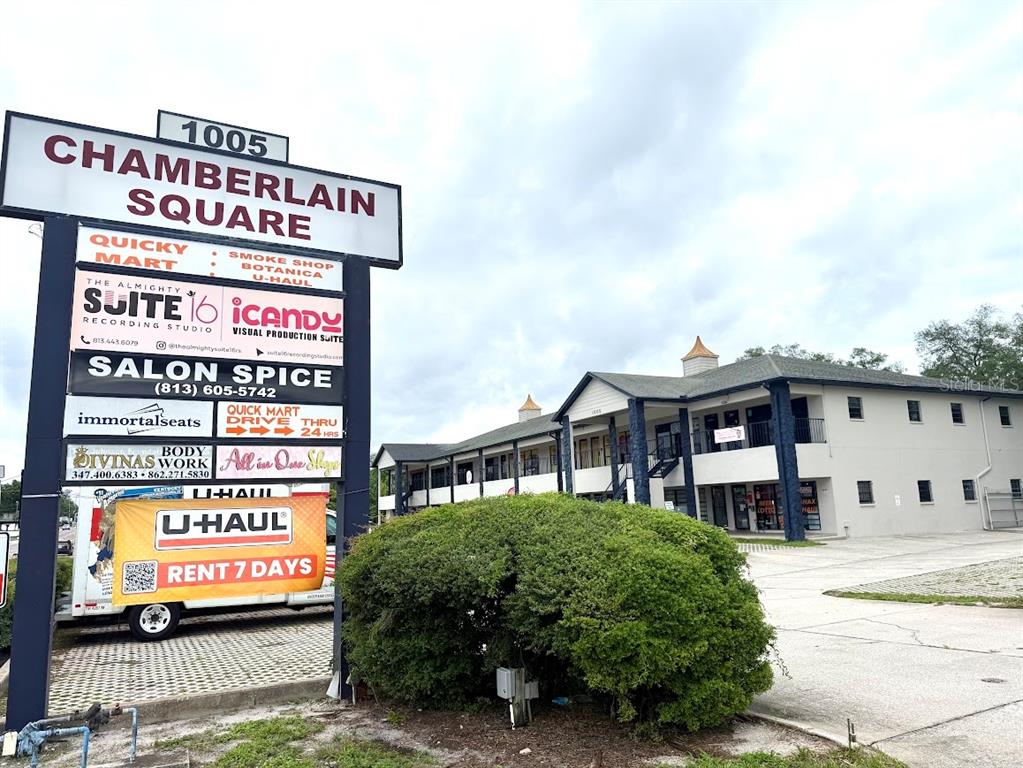 A multi-tenant commercial building stands behind a large sign listing various businesses and services — 1005 W BUSCH BOULEVARD, TAMPA, FL