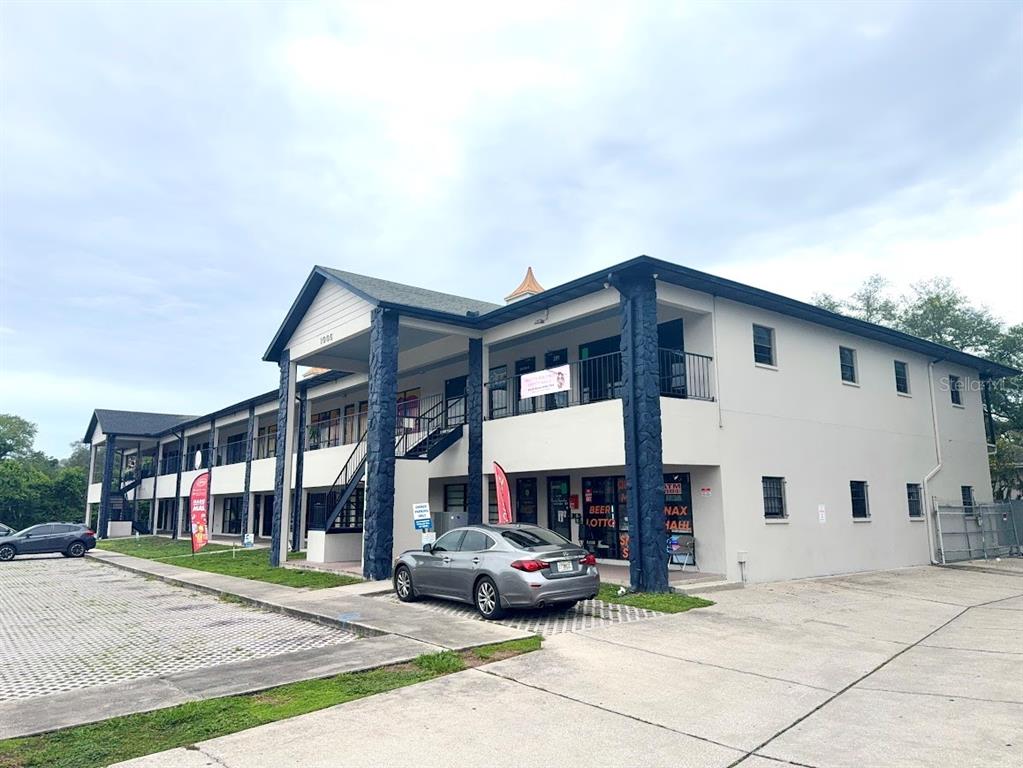 A two-story commercial building with a gray sedan parked in front — 1005 W BUSCH BOULEVARD, TAMPA, FL