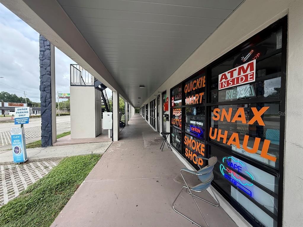 A covered walkway leads past a storefront with large windows displaying various business signs — 1005 W BUSCH BOULEVARD, TAMPA, FL