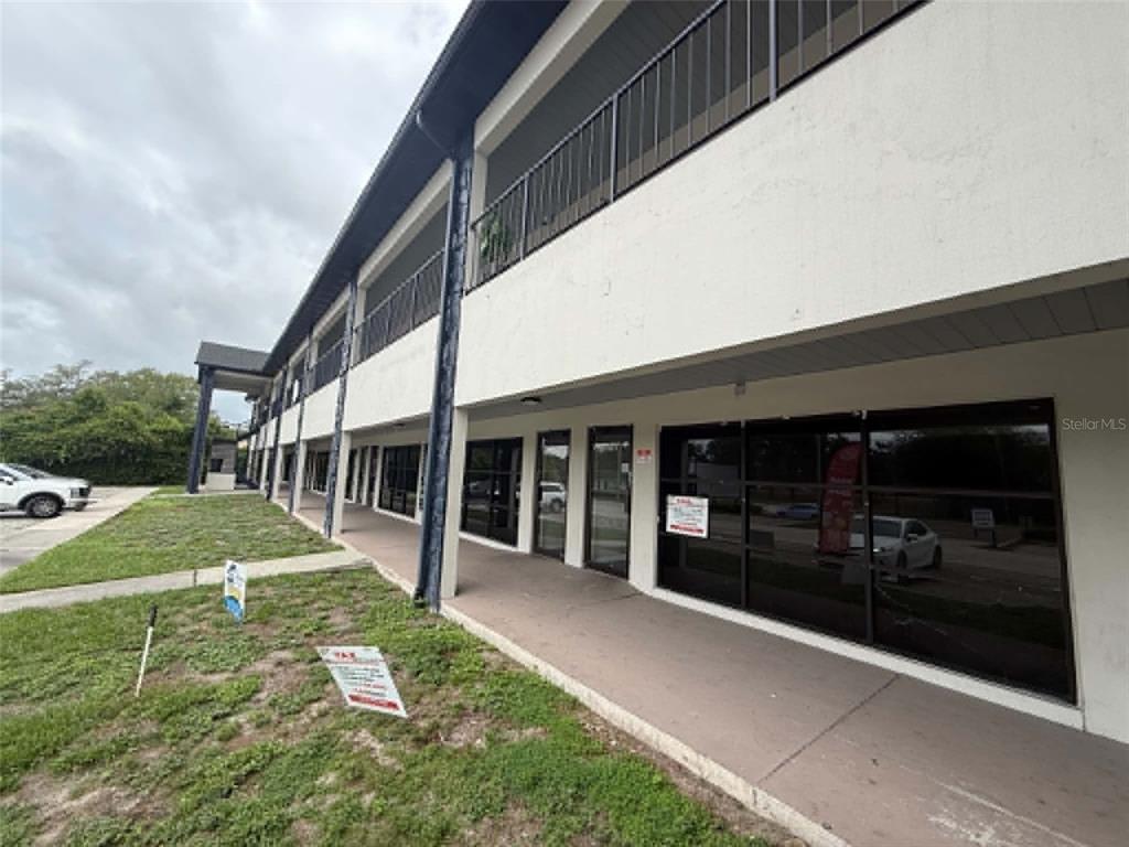 A two-story commercial building features a covered walkway and glass storefronts on the ground level — 1005 W BUSCH BOULEVARD, TAMPA, FL