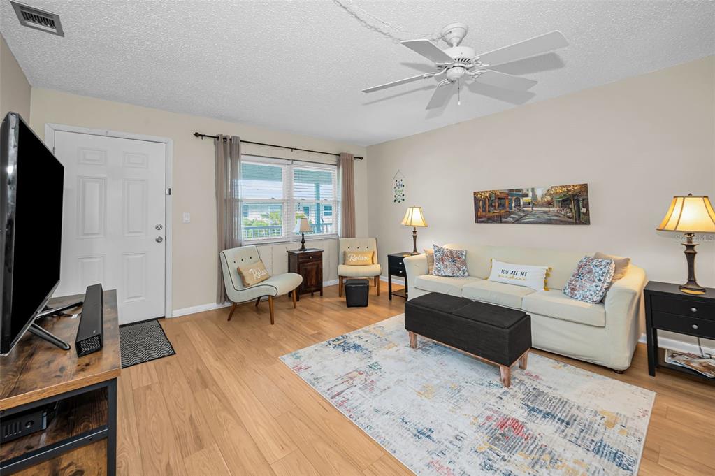 A living room features light wood flooring, a beige sofa, and a ceiling fan — 5227 81ST LANE N UNIT 22, ST PETERSBURG, FL
