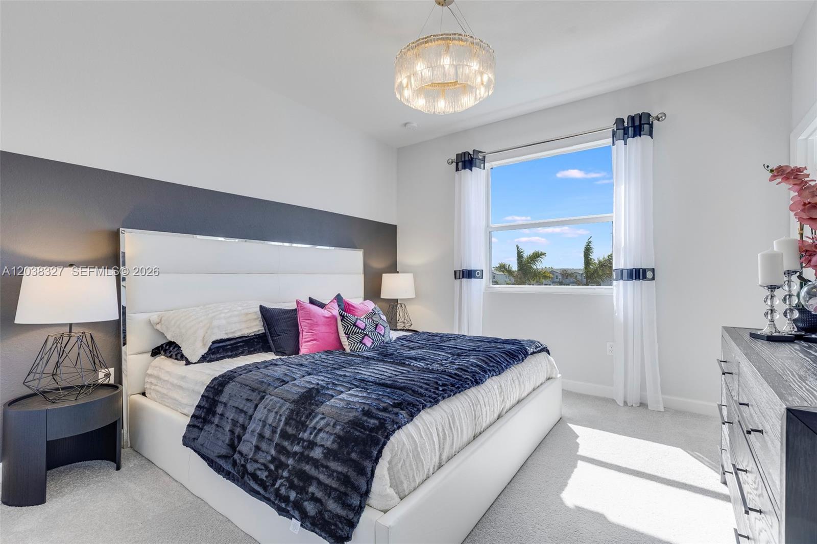 A modern bedroom features a white upholstered bed, dark accent wall, and a crystal chandelier — 35624 SW 178 PL, Miami FL 33034, MIAMI, FL