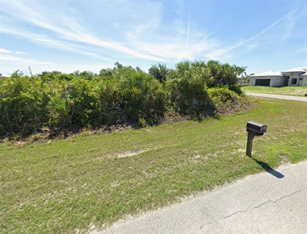 A grassy, undeveloped residential lot features dense vegetation and a single mailbox by the road — 14159 FORT MYERS AVENUE, PORT CHARLOTTE, FL