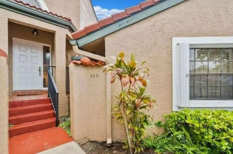 The exterior of a house features a white front door, red steps, and a window — 9231 W Sunrise Boulevard, Plantation FL 33322, PLANTATION, FL