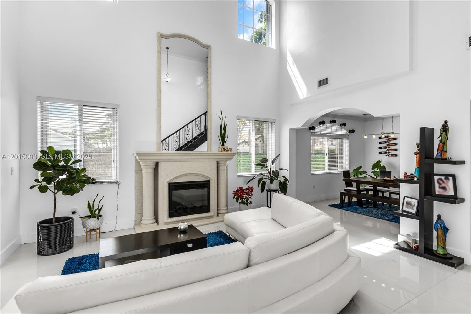 A bright living room features a white sectional sofa, a fireplace, and high ceilings — 15395 SW 23rd St, Miami FL 33185, MIAMI, FL