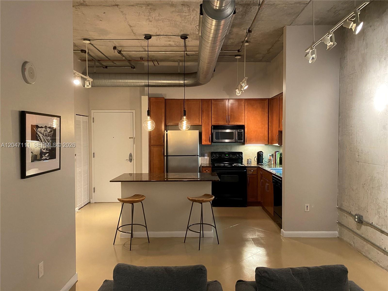 An open-concept kitchen features wood cabinets, stainless steel appliances, and an industrial exposed ceiling — 2001 Biscayne Blvd # 3203, Miami FL 33137, MIAMI, FL