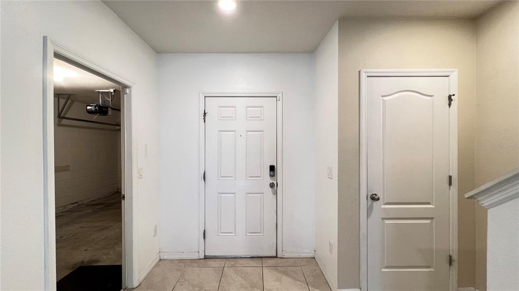 An entryway features a white front door, a doorway to a garage, and a closet door — 9017 ALBA LANE, KISSIMMEE, FL
