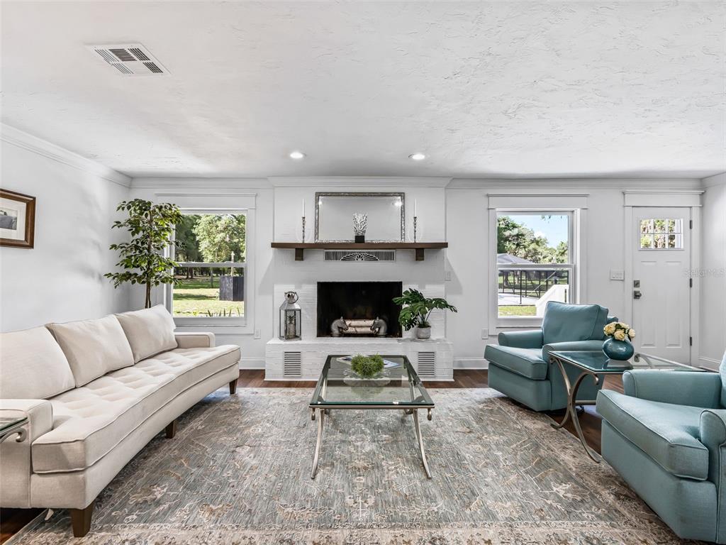 A living room features a white brick fireplace, a beige sofa, and two blue armchairs — 10660 E BUSHNELL ROAD, FLORAL CITY, FL