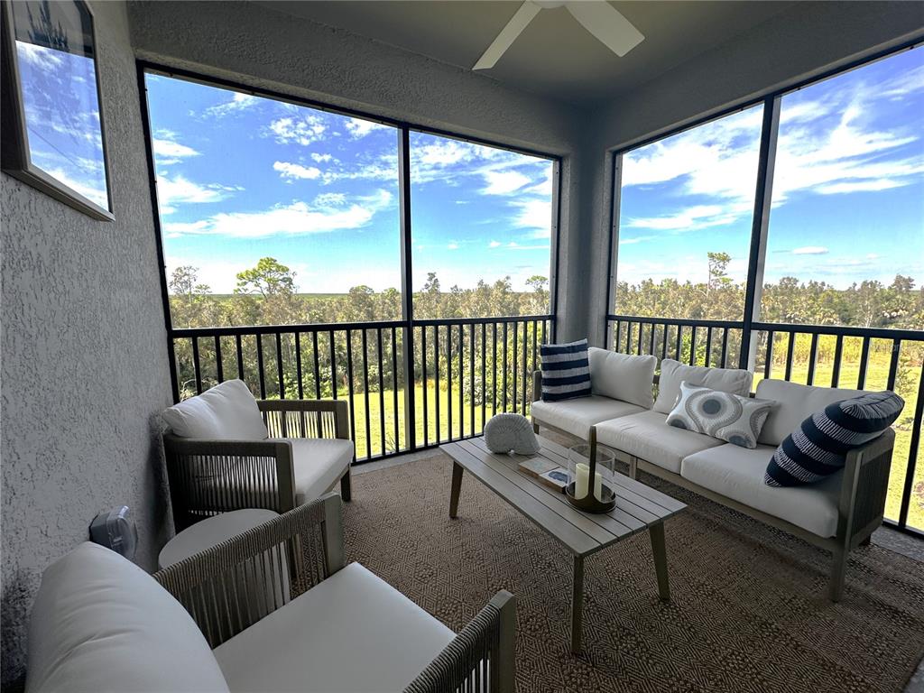 A screened-in porch features outdoor furniture, a coffee table, and views of a wooded area — 14201 HERITAGE LANDING BOULEVARD UNIT 1338, PUNTA GORDA, FL