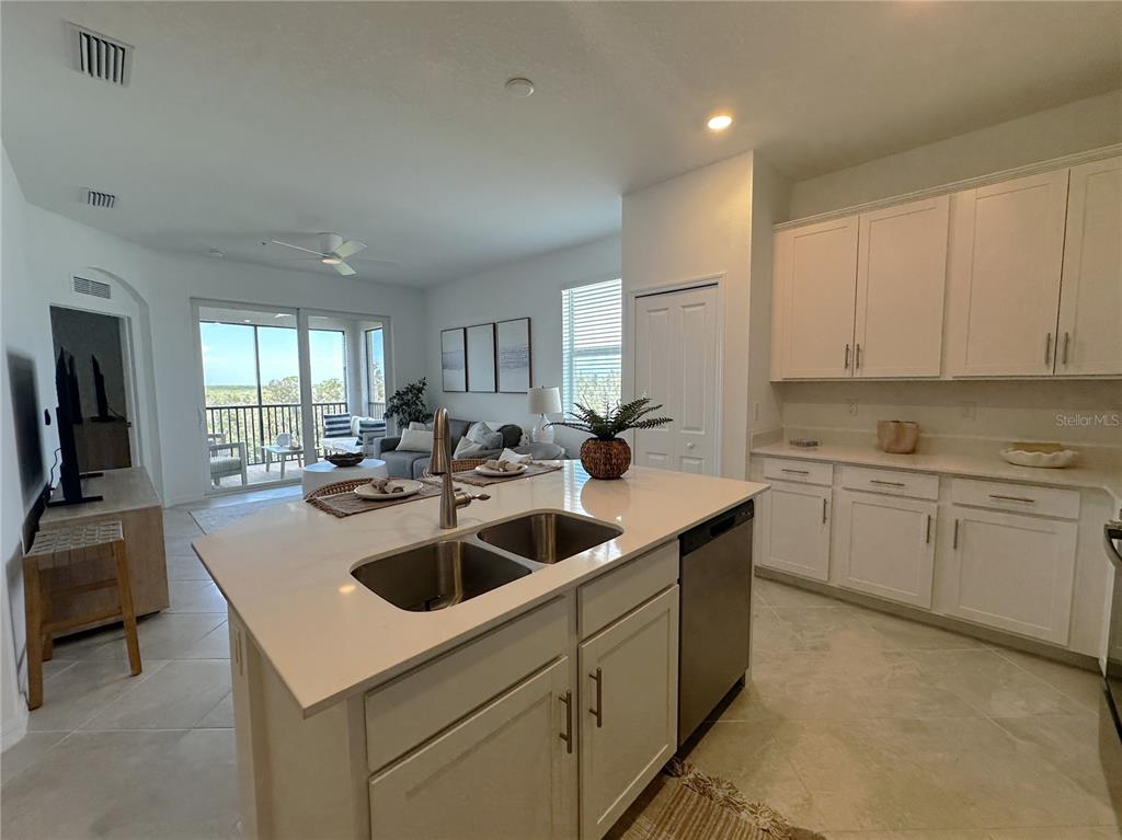 A kitchen with a central island and white cabinets overlooks an open living area — 14201 HERITAGE LANDING BOULEVARD UNIT 1338, PUNTA GORDA, FL