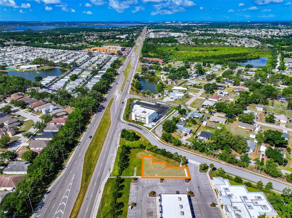 An aerial view shows a vacant, L-shaped lot highlighted in orange next to a parking lot — 10030 US HIGHWAY 301 N, PARRISH, FL
