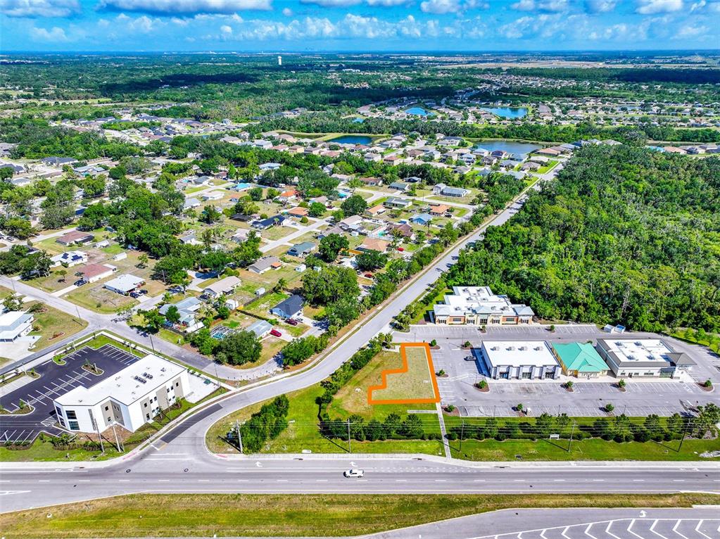 An aerial view shows a vacant lot outlined in orange between two commercial buildings — 10030 US HIGHWAY 301 N, PARRISH, FL