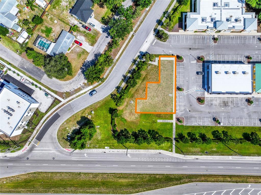 An aerial view shows a vacant, irregularly shaped lot outlined in orange next to a parking lot — 10030 US HIGHWAY 301 N, PARRISH, FL