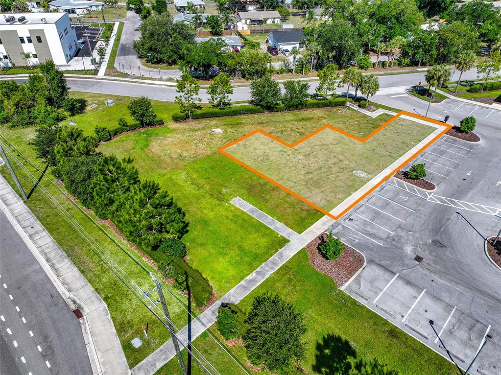 An aerial view shows an empty, L-shaped grass lot adjacent to a paved parking area — 10030 US HIGHWAY 301 N, PARRISH, FL