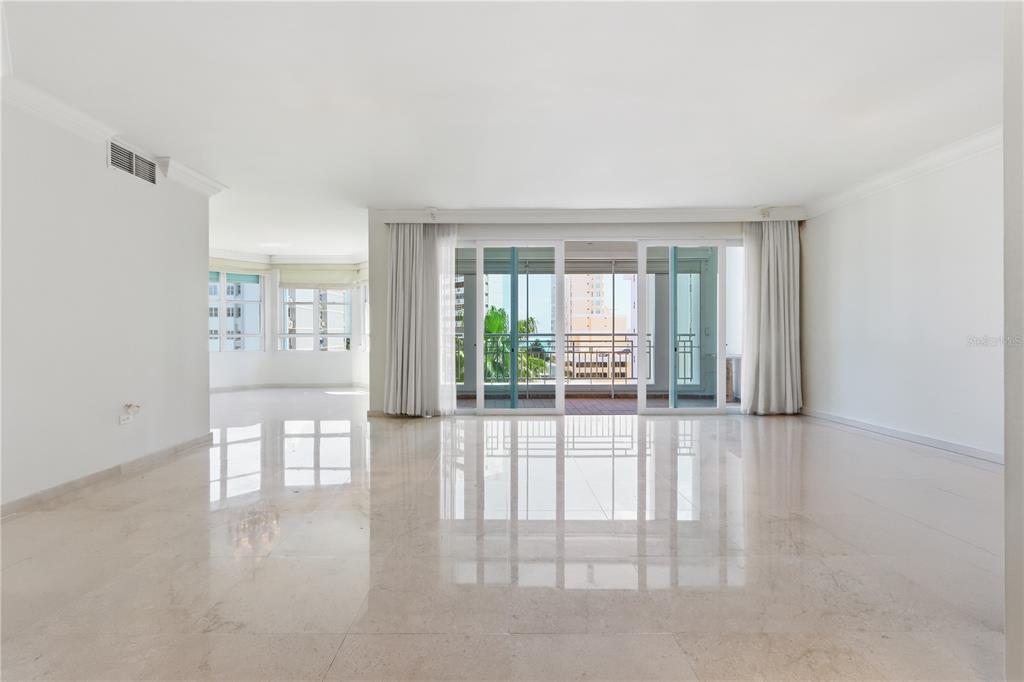 A spacious, empty room features polished marble floors, white walls, and large sliding glass doors — 1754 MCCLEARY AVENUE UNIT 602, SAN JUAN, PR
