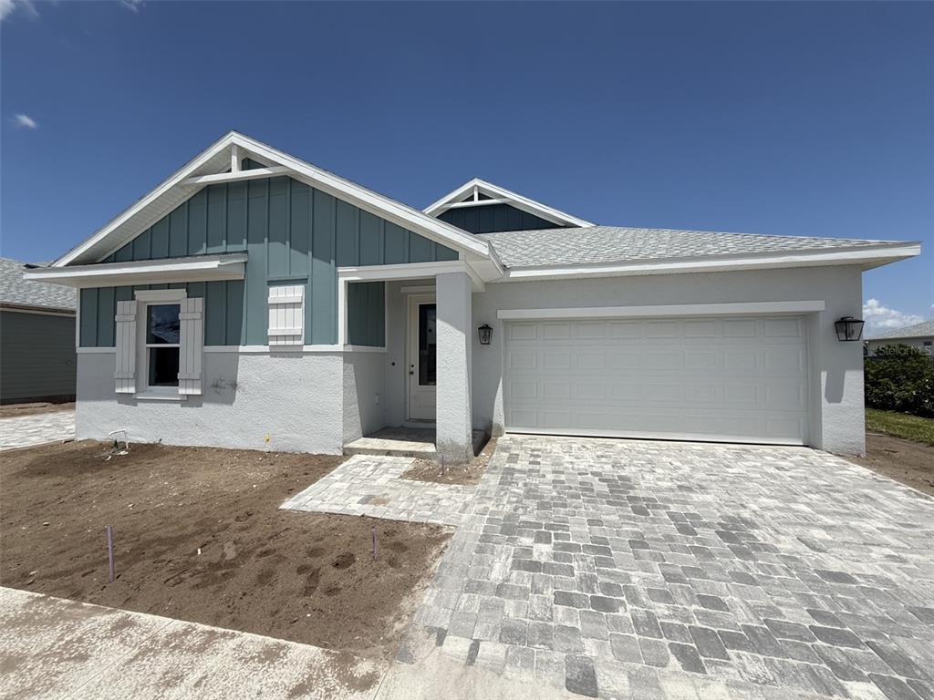 A single-story house features a blue vertical-siding gable, stucco walls, and a paved driveway — 5268 COLONY VISTA DRIVE, APOLLO BEACH, FL