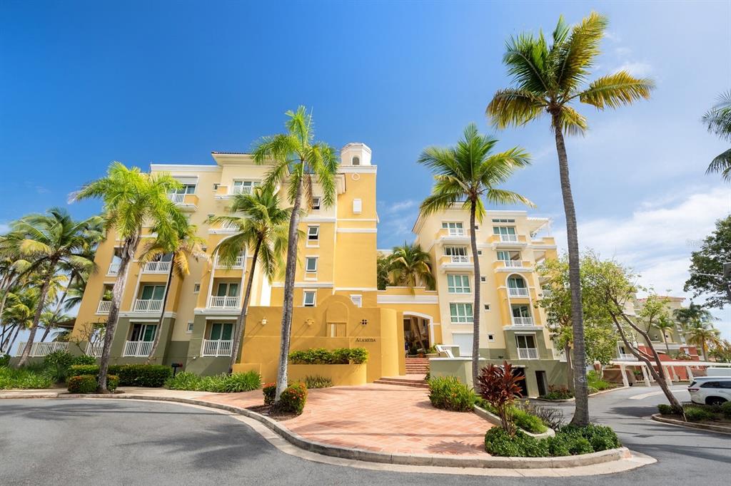 A multi-story yellow apartment building with palm trees and a paved driveway in the foreground — 400 OCEAN DRIVE UNIT 423, HUMACAO, PR