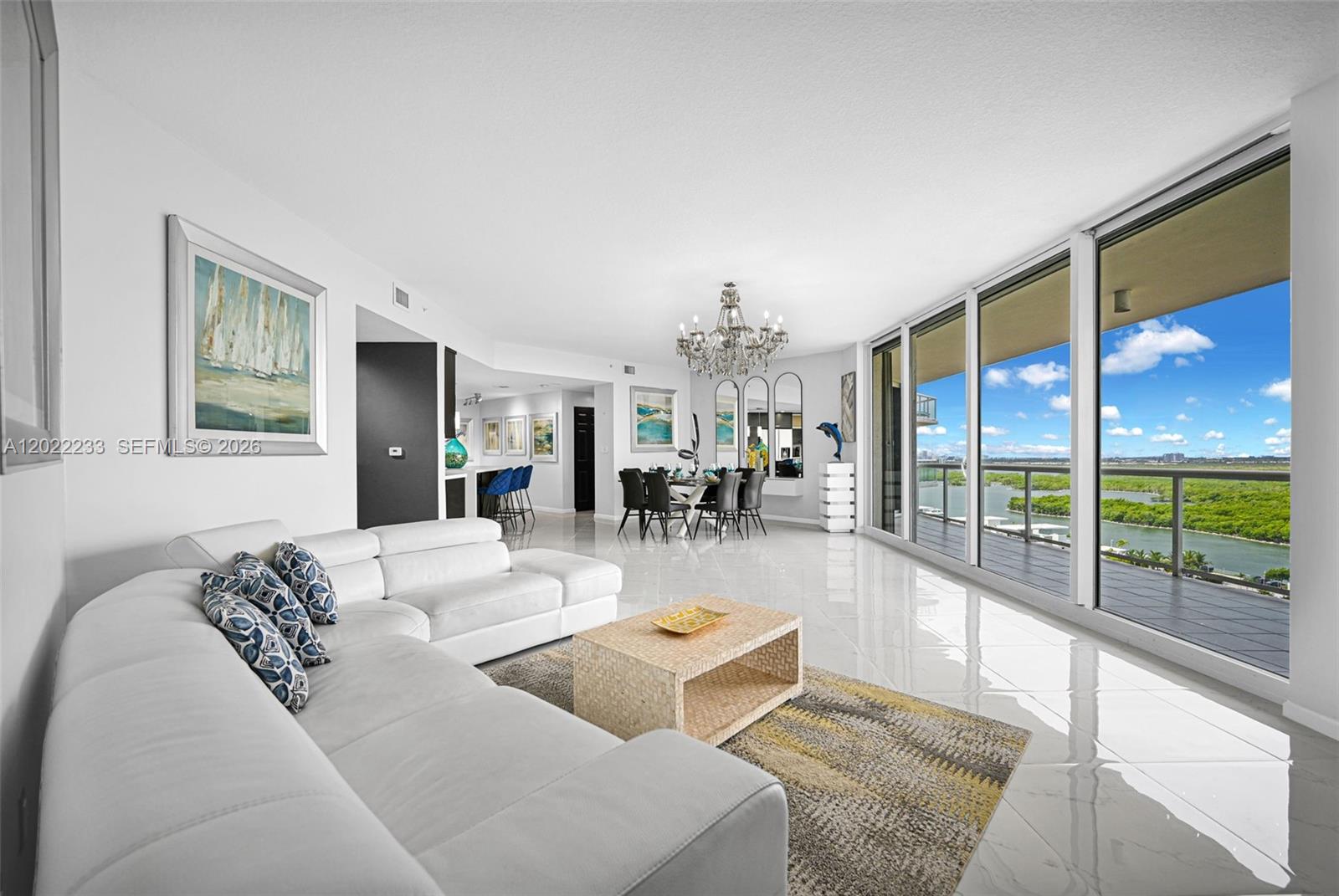 A bright living and dining area features white tile floors, a sectional sofa, and balcony views — 6001 N Ocean Dr # 1203, Hollywood FL 33019, HOLLYWOOD, FL
