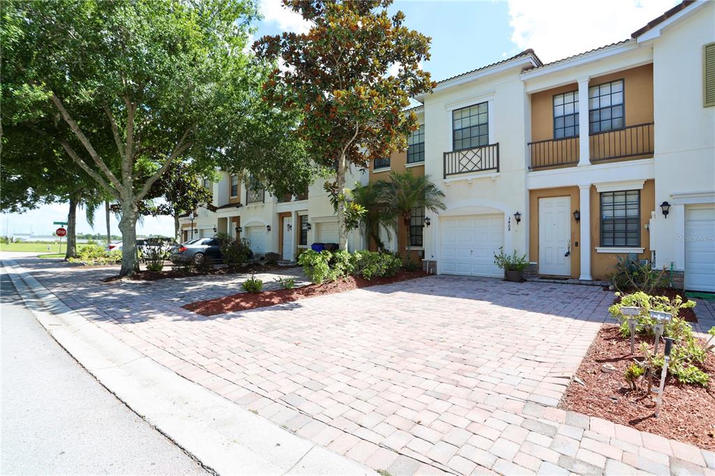 A row of two-story townhomes with paved driveways and attached garages under a blue sky — 3408 ALLEGRA CIRCLE, ST CLOUD, FL