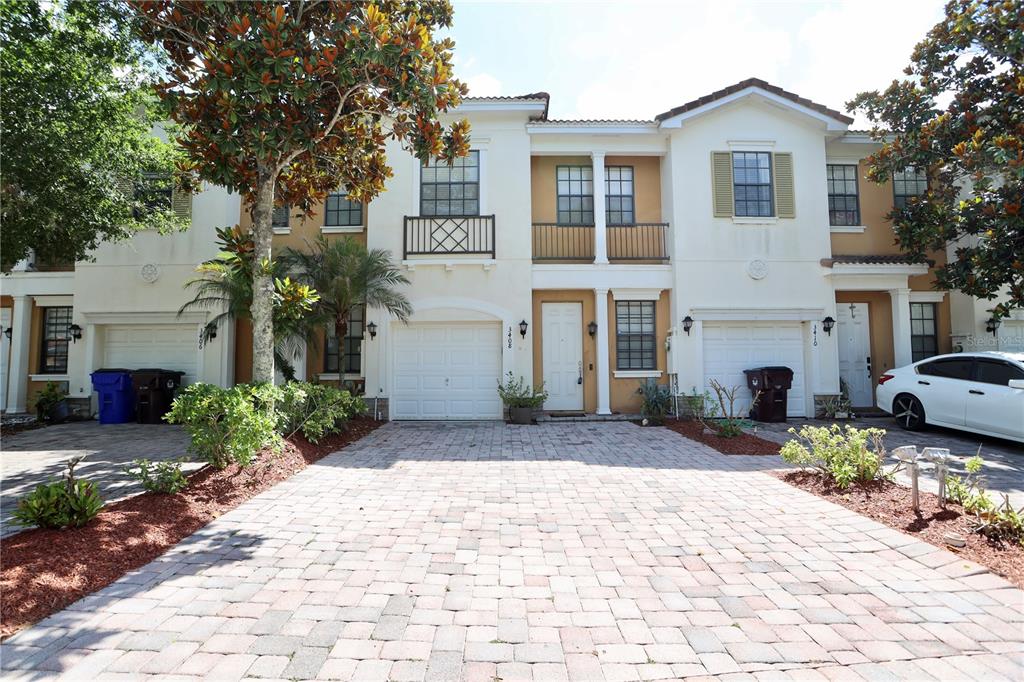 A row of two-story townhouses with white stucco facades, arched garage doors, and paved driveways — 3408 ALLEGRA CIRCLE, ST CLOUD, FL
