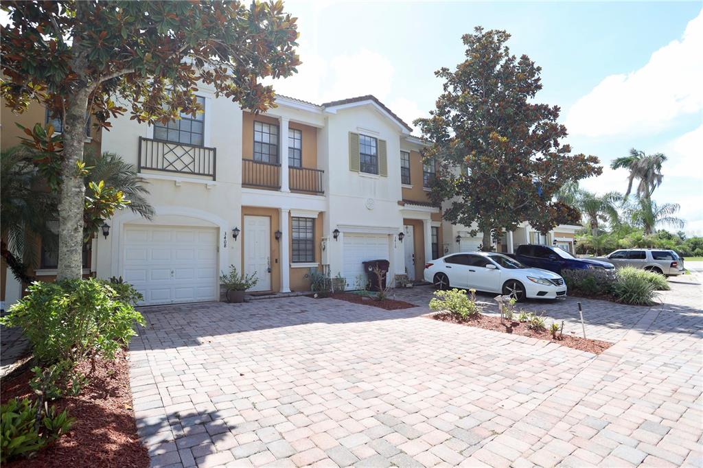 A row of two-story townhomes with paved driveways and attached garages under a blue sky — 3408 ALLEGRA CIRCLE, ST CLOUD, FL