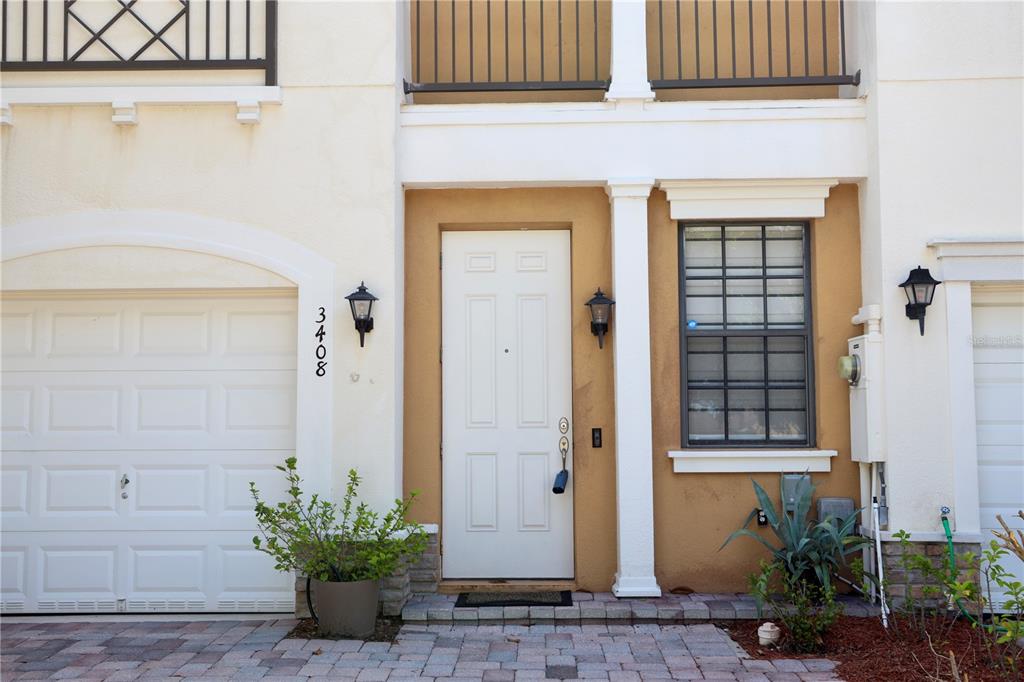 The exterior of a townhouse features a white front door, a garage, and a window — 3408 ALLEGRA CIRCLE, ST CLOUD, FL