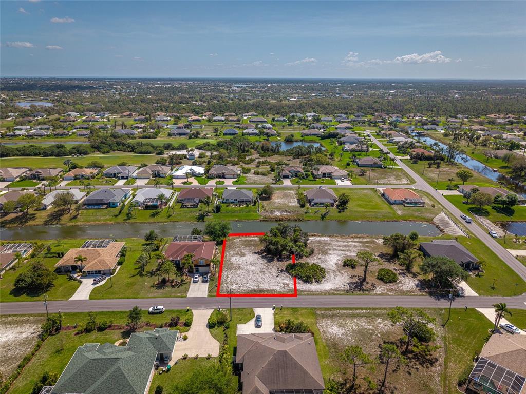 An aerial view shows a vacant residential lot outlined in red next to a canal — 47 MEDALIST LANE, ROTONDA WEST, FL