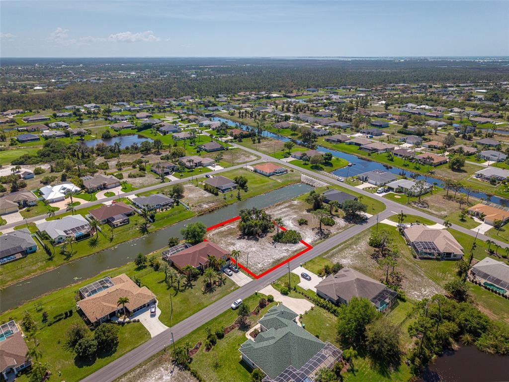 An aerial view shows a vacant residential lot outlined in red next to a canal — 47 MEDALIST LANE, ROTONDA WEST, FL