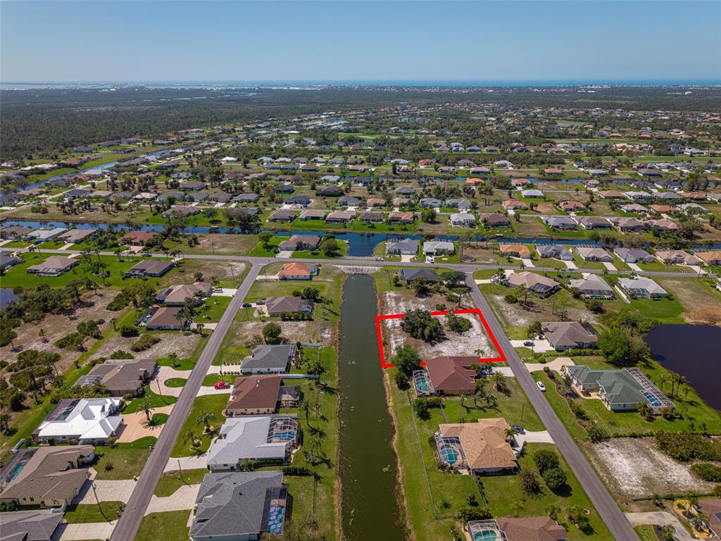 An aerial view shows a vacant residential lot outlined in red beside a canal — 47 MEDALIST LANE, ROTONDA WEST, FL