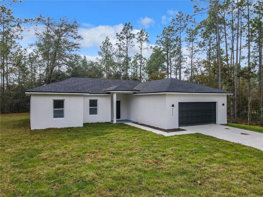 A single-story white stucco house with a dark roof and a two-car garage — 8070 SW 131ST LANE, OCALA, FL