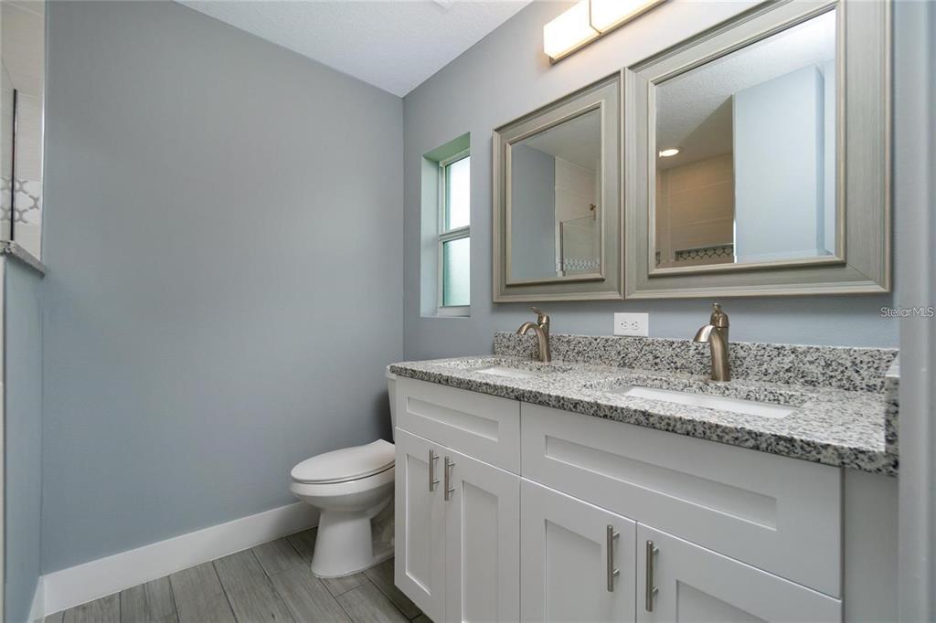 A bathroom with a double vanity, granite countertop, gray walls, and a toilet — 0 LONGFELLOW LANE, NORTH PORT, FL