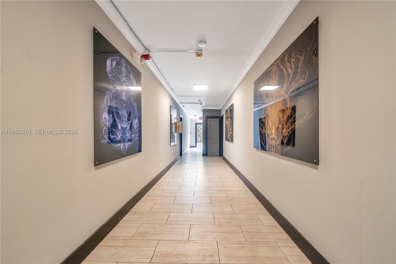 A hallway features light-colored tile flooring, beige walls, and two large abstract art pieces — 1554 SW 5th St # 11c, Miami FL 33135, MIAMI, FL