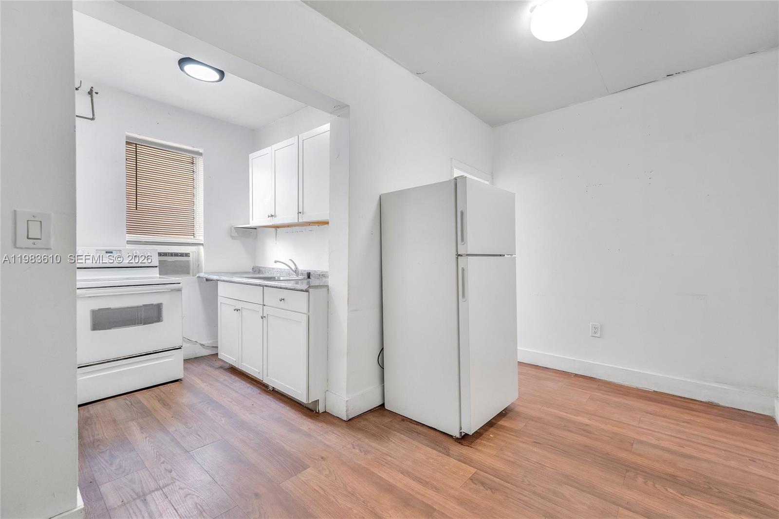 A small kitchen features white cabinets, a white stove, and a refrigerator on wood flooring — 1554 SW 5th St # 11c, Miami FL 33135, MIAMI, FL