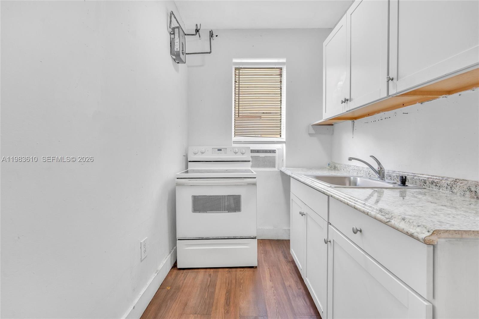 A small kitchen features white cabinets, a white stove, and a granite countertop — 1554 SW 5th St # 11c, Miami FL 33135, MIAMI, FL