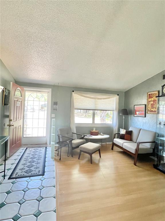 A living room features light wood flooring, a tile entryway, and a window with blinds — 6944 LARCHMONT AVE, NEW PORT RICHEY, FL