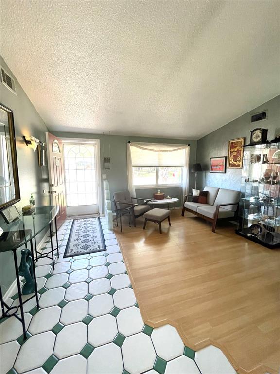 A living room features a mix of tiled and wood flooring, a sofa, and seating — 6944 LARCHMONT AVE, NEW PORT RICHEY, FL