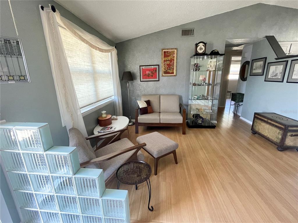 A living room features light wood flooring, a glass block wall, and a display cabinet — 6944 LARCHMONT AVE, NEW PORT RICHEY, FL