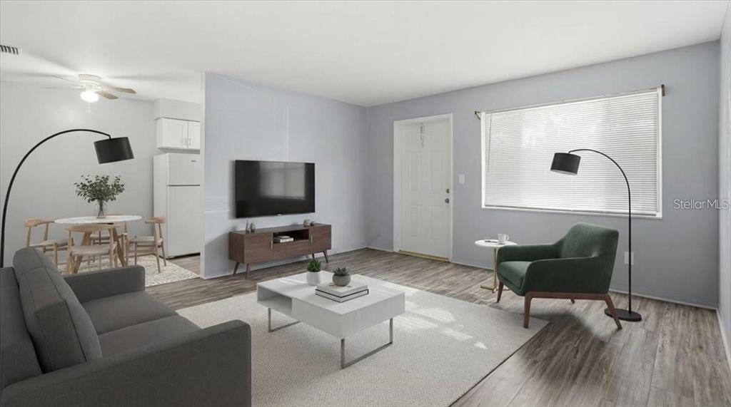 A living room with gray walls, wood-look flooring, a white coffee table, and a green chair — 5991 FAIRFIELD AVENUE S, GULFPORT, FL