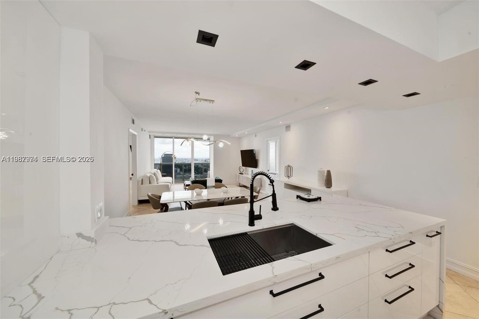 A modern kitchen island with a marble countertop overlooks an open-concept living and dining area — 1830 S Ocean Dr # 4704, Hallandale Beach FL 33009, HALLANDALE BEACH, FL