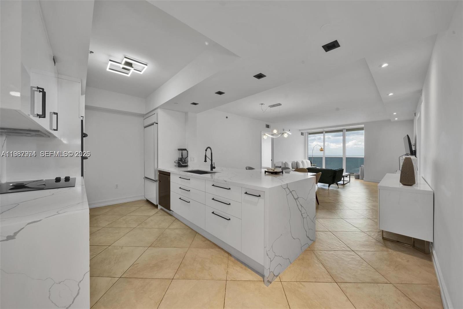 A modern kitchen with white marble countertops and cabinetry opens into a living area — 1830 S Ocean Dr # 4704, Hallandale Beach FL 33009, HALLANDALE BEACH, FL
