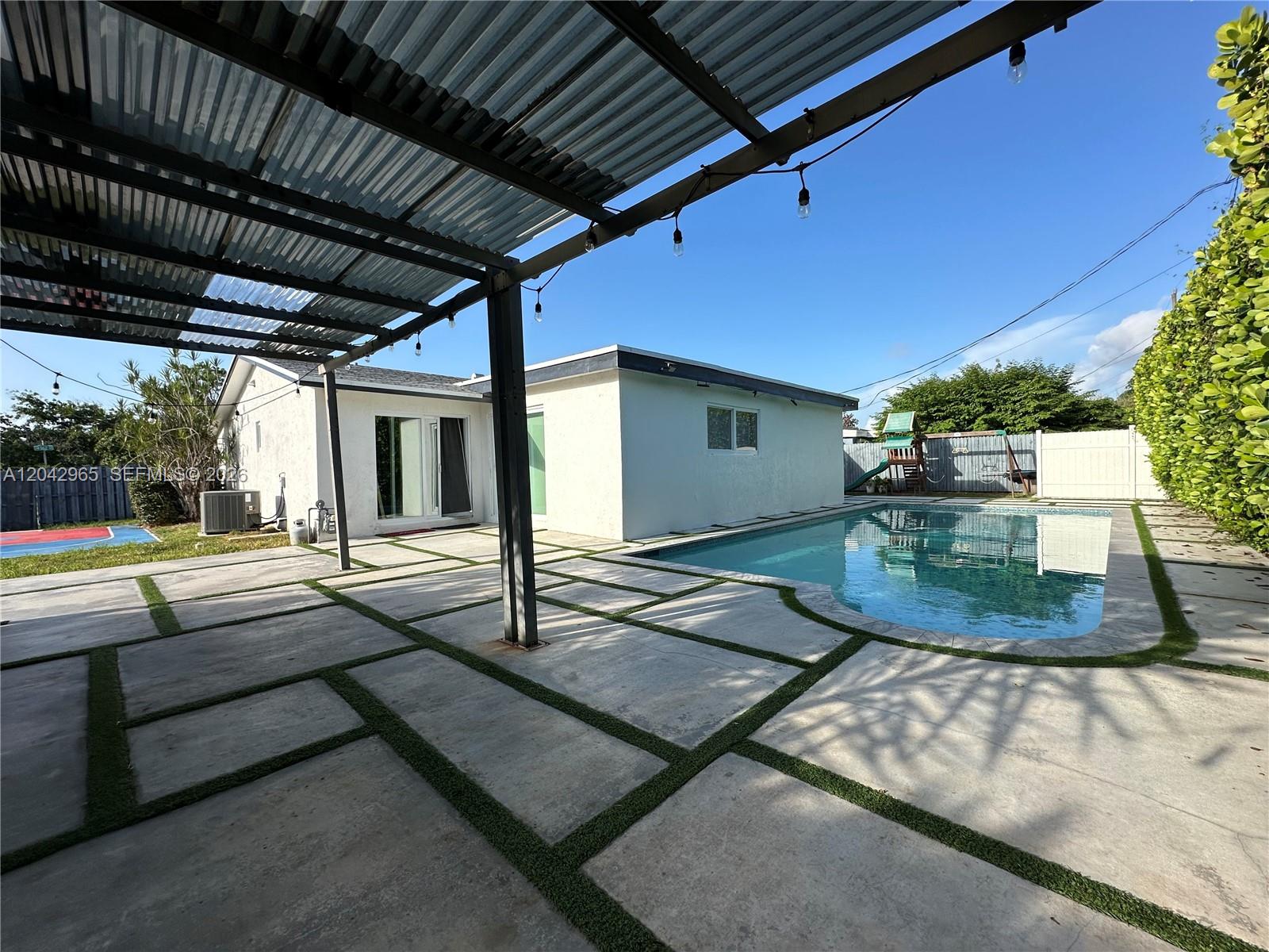 A backyard features a swimming pool, a covered patio with concrete pavers, and a house — 10010 SW 162nd St, Miami FL 33157, MIAMI, FL