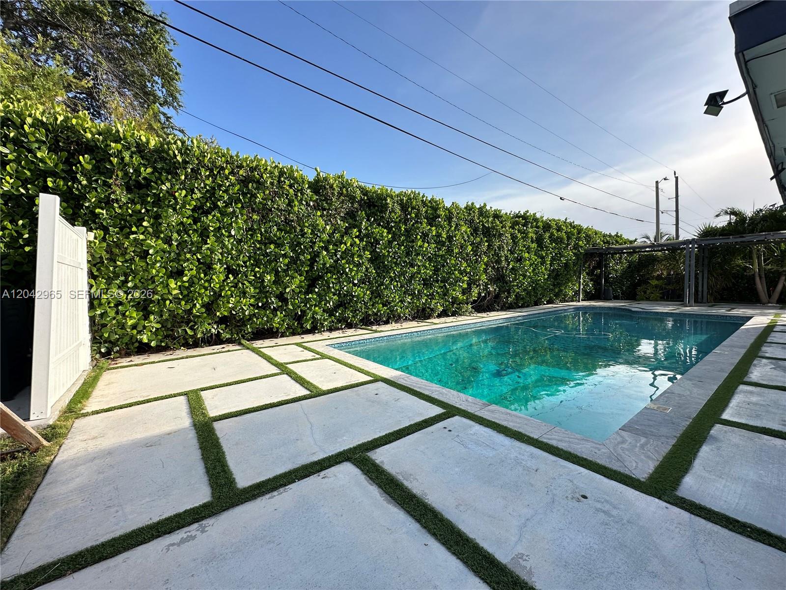 A rectangular swimming pool is surrounded by concrete pavers with artificial grass inlays — 10010 SW 162nd St, Miami FL 33157, MIAMI, FL