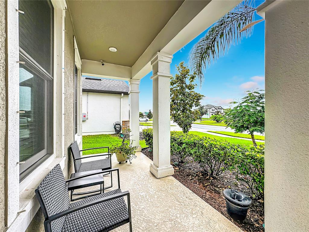A covered front porch features two chairs, white columns, and a view of the neighborhood — 13222 MOSS GRASS WAY, RIVERVIEW, FL