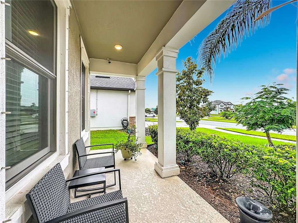 A covered front porch features two wicker chairs, a small table, and white columns — 13222 MOSS GRASS WAY, RIVERVIEW, FL