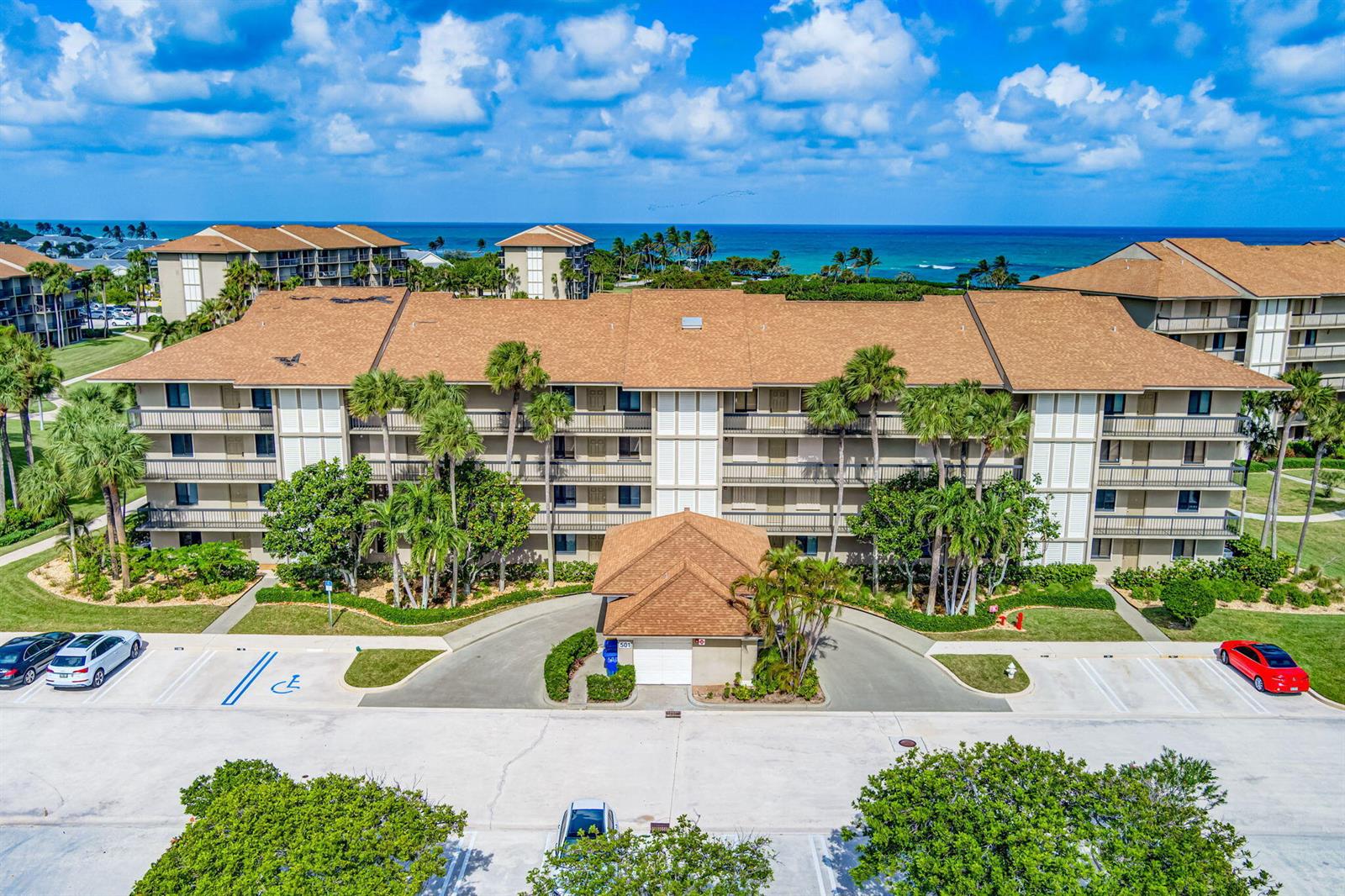 An aerial view shows a multi-story apartment building with a brown roof and palm trees — 501 S Seas Drive # 202, Jupiter FL 33477, JUPITER, FL