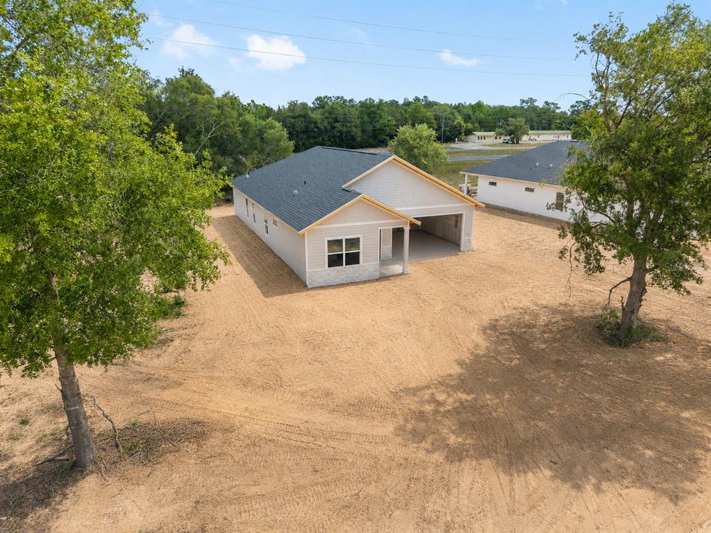 An exterior view of a new single-story house with a garage and sandy yard — 13291 NE 54TH STREET, WILLISTON, FL